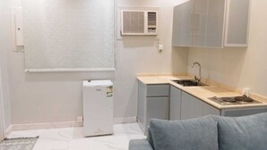 A compact kitchen with a sink, cabinets, and a small refrigerator. - Assistanceforfurnishedresidential units (Jeddah)