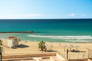 A beach with a lifeguard tower, umbrellas, and a clear view of the ocean. - Haifa Beachside Stay by Sea N' Rent (Haifa)