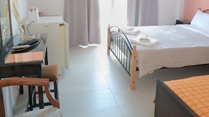 A hotel room with a bed, a desk, a chair, a television, and a window with curtains. - GOLDEN BEACH (Aegina)