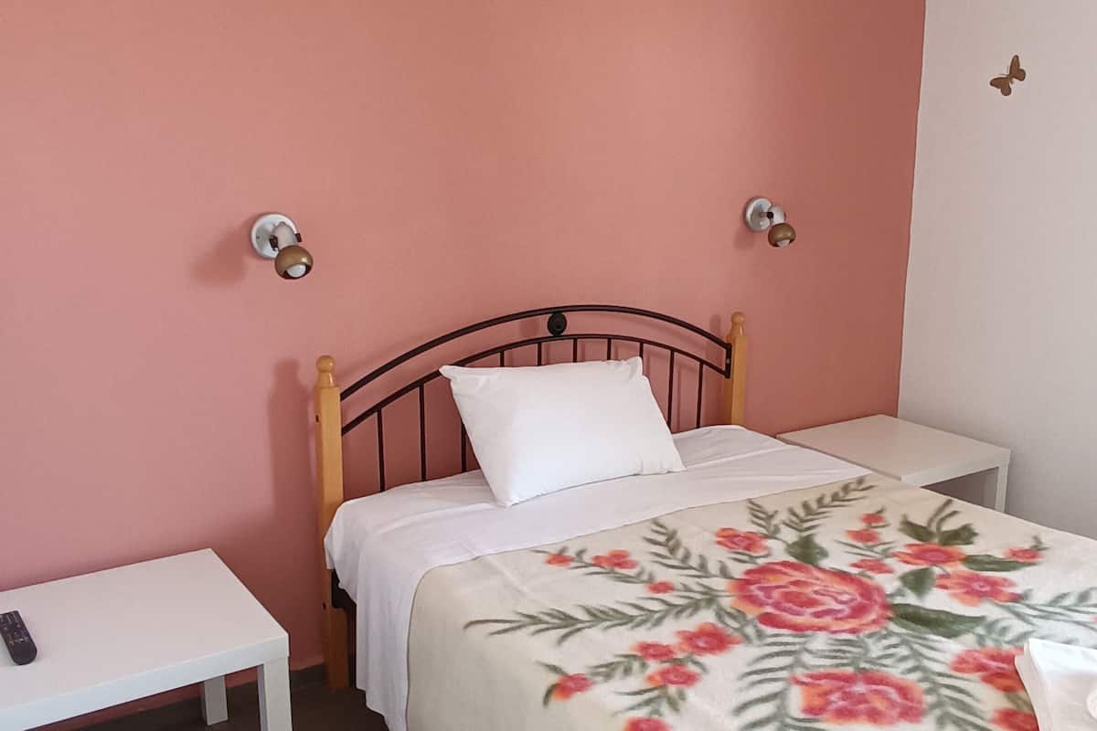 Una cama individual con una colcha estampada, una mesita de noche y una lámpara de noche.