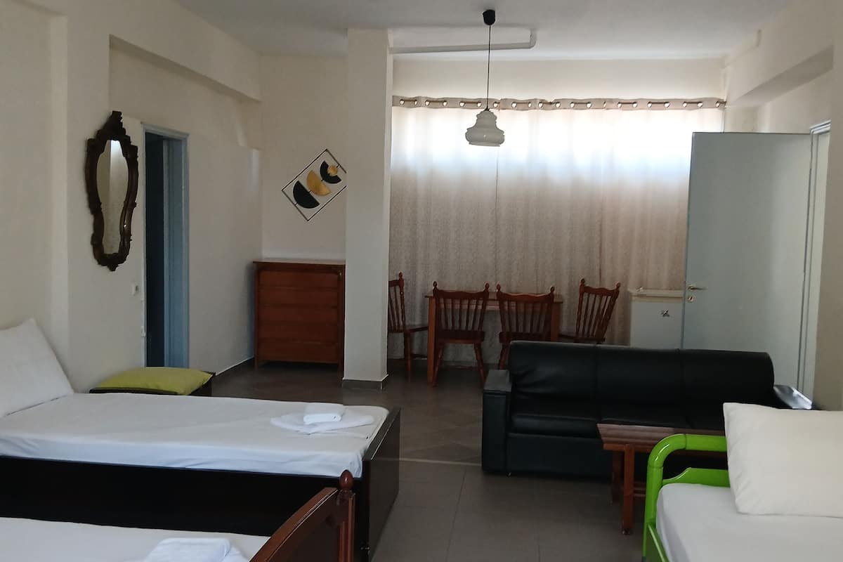 Habitación de hotel con dos camas, un escritorio, una silla, un sofá y un espejo.