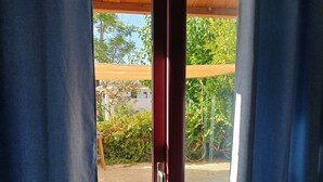 A sliding glass door leading to an outdoor area with a wooden pergola and greenery. - GOLDEN BEACH (Aegina)