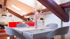 Een moderne keuken met rode kastjes, een glazen tafel en twee stoelen.