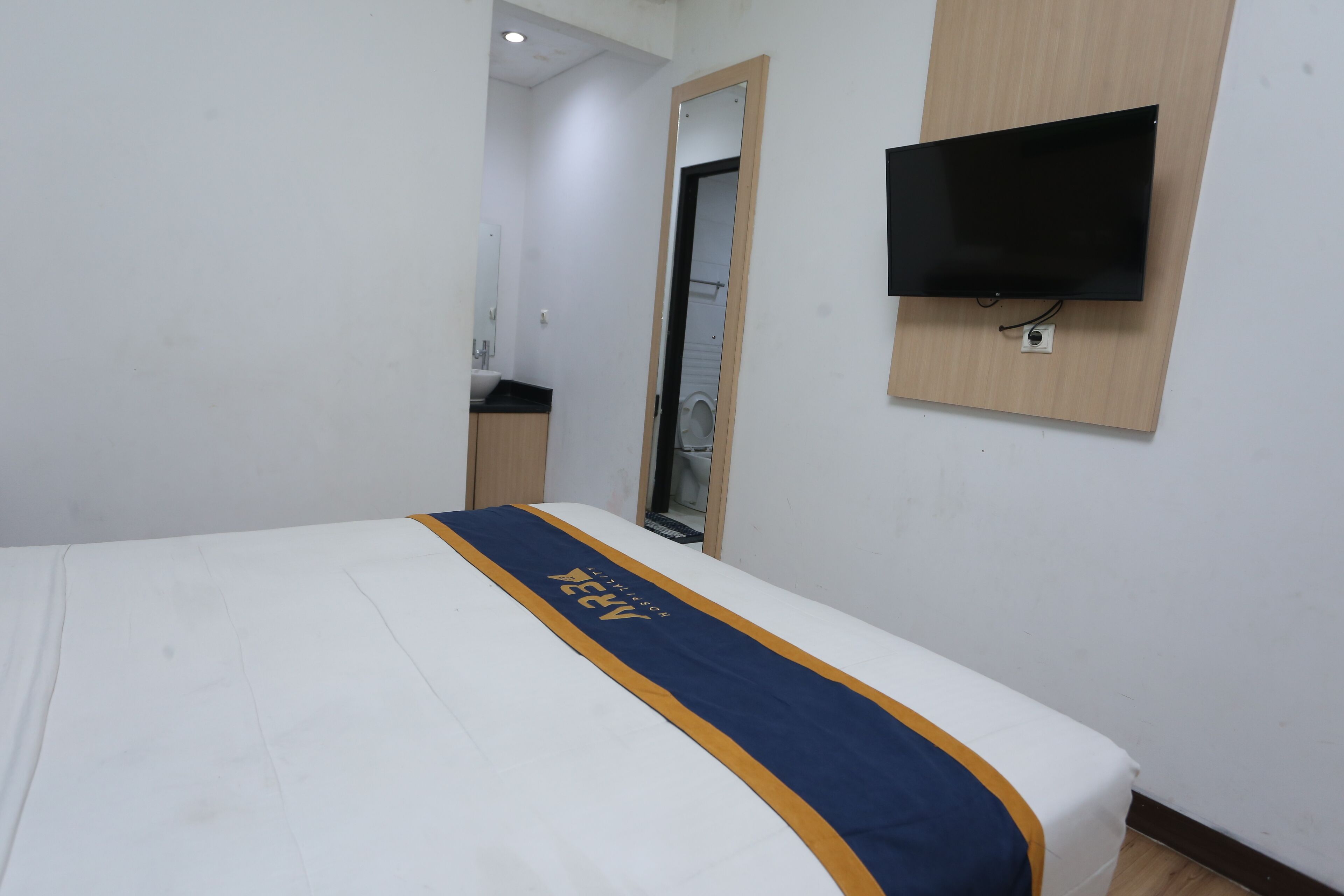 A hotel room with a bed, a TV mounted on the wall, and a mirror.
