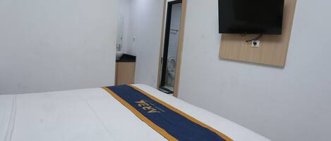 A hotel room with a bed, a TV mounted on the wall, and a mirror.