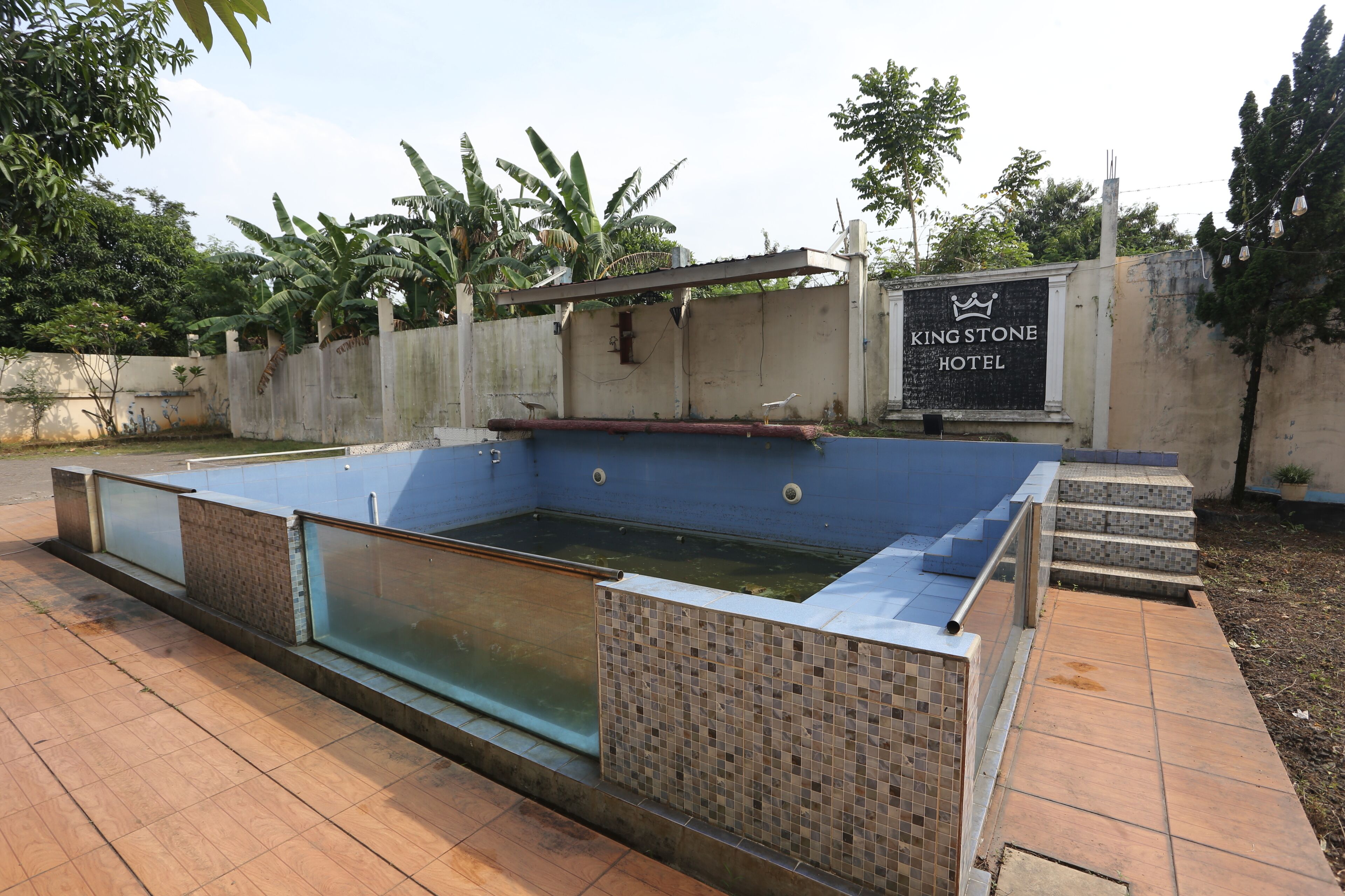 A swimming pool with a tiled border and a sign for the King Stone Hotel.