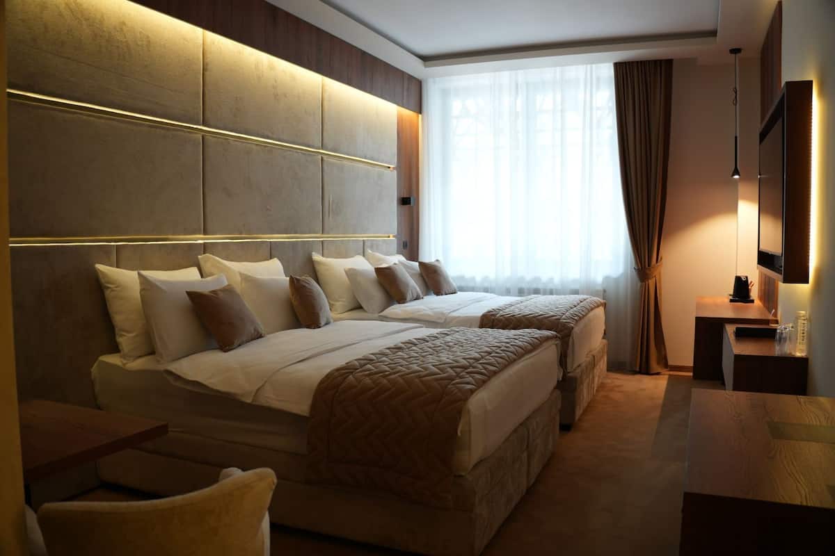 Habitación de hotel con dos camas, un escritorio y una televisión.