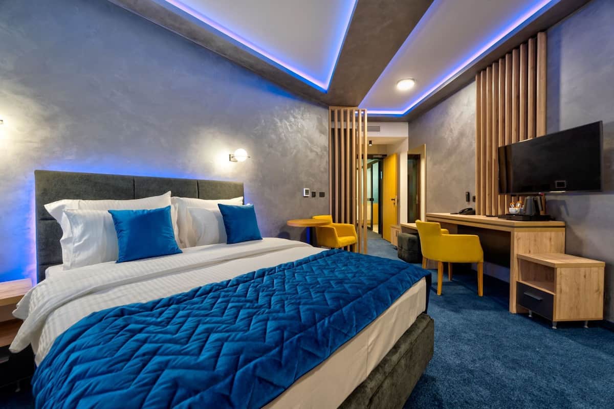 Una habitación de hotel moderna con una cama grande, un escritorio y un televisor.