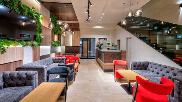 A modern hotel lobby with seating areas, a reception desk, and a staircase. - Aria City Boutique Hotel (Užice)