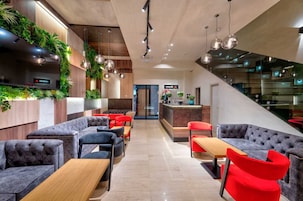Un moderno hall de hotel con áreas de estar, un mostrador de recepción y una escalera.