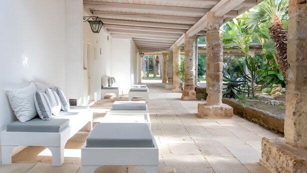 A covered outdoor seating area with white benches and a stone column structure. - Holiday Home 'Villa Riggia - La Masseria' with Wi-Fi and Air Conditioning (Nardò)