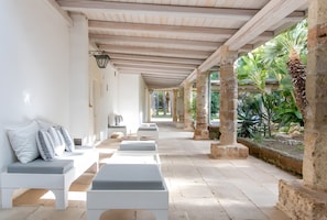 A covered outdoor seating area with white benches and a stone column structure. - Holiday Home 'Villa Riggia - La Masseria' with Wi-Fi and Air Conditioning (Nardò)