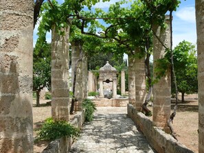 A stone pathway leading to a historical structure with arches and columns, surrounded by greenery. - Villa 'Riggia - Dependance Stalla' with Shared Pool, Private Terrace, and Air Conditioning (Nardò)