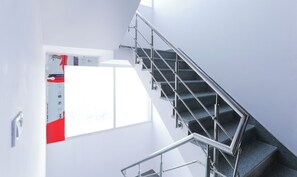 A staircase with metal railings and a window with a view of a building. - Hotel TMS Residency (New Delhi)