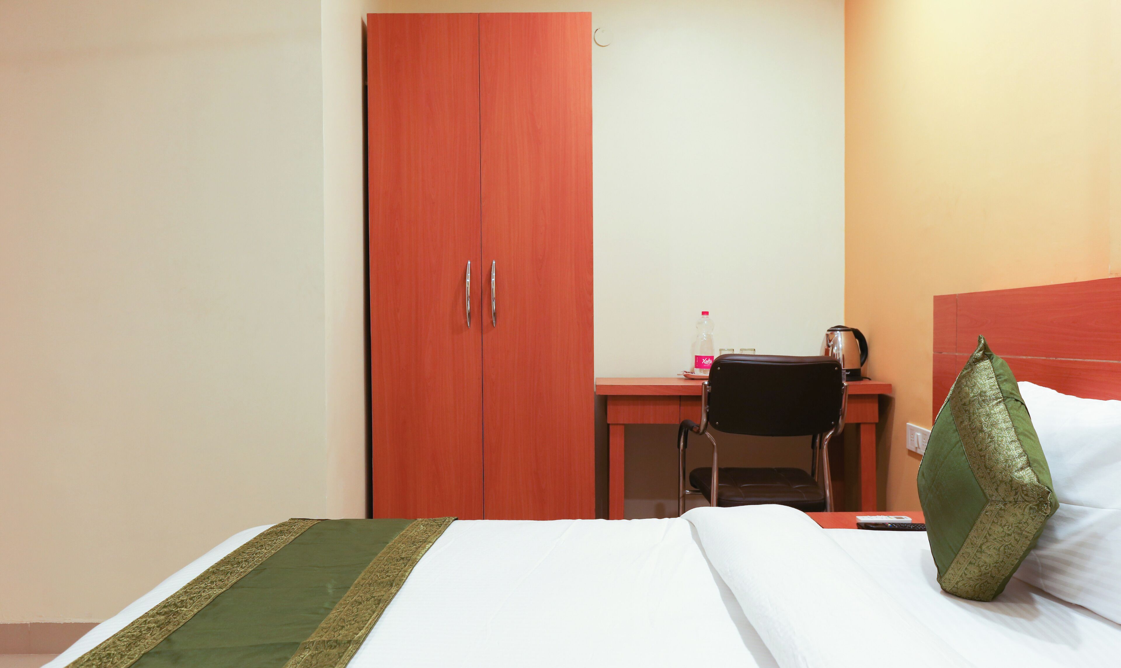 A hotel room with a bed, a desk, a chair, and a wardrobe.