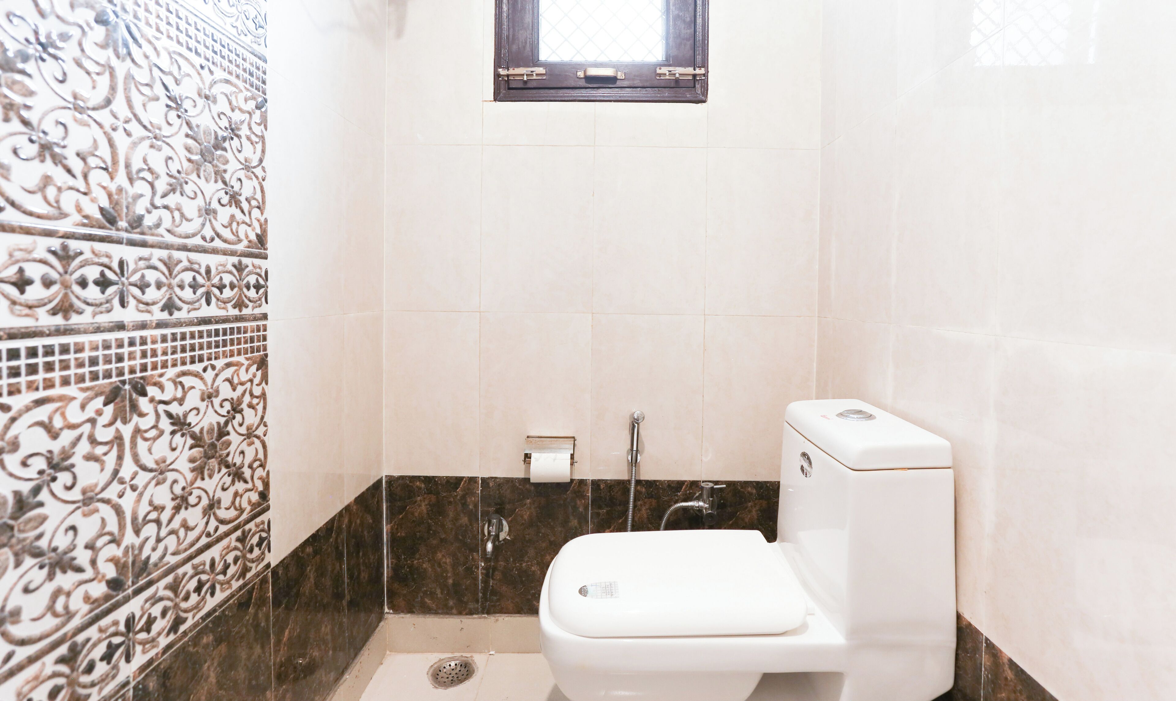 A bathroom with a toilet, a shower, and a window.