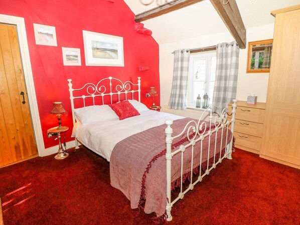 A bedroom with a red wall, a white metal bed frame, a red carpet, and a wooden wardrobe. - Little Bargate (Hope Valley)