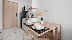 Une cuisine moderne avec une table en bois mise pour deux personnes, un four à micro-ondes et une cuisinière.