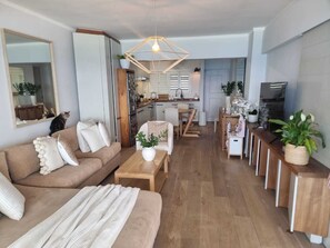 Ein modernes Wohnzimmer mit einer Couch, einem Couchtisch und einem Essbereich mit einer Küche im Hintergrund.