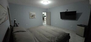 A bedroom with a bed, a TV mounted on the wall, and a door leading to another room. - Your Dream Escape to Nature & Fun at Villa Palmeras in Playa Juan Hombron (El Chiru)