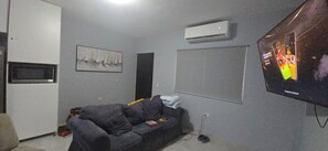 A living room with a grey couch, a flat-screen TV, an air conditioner, and a framed picture on the wall. - Your Dream Escape to Nature & Fun at Villa Palmeras in Playa Juan Hombron (El Chiru)