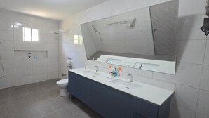 A modern bathroom with a shower, toilet, and a vanity with a mirror. - Your Dream Escape to Nature & Fun at Villa Palmeras in Playa Juan Hombron (El Chiru)