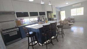 A modern kitchen with a central island, bar stools, and a dining table. - Your Dream Escape to Nature & Fun at Villa Palmeras in Playa Juan Hombron (El Chiru)