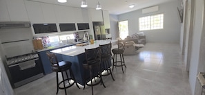 A modern kitchen with a central island, bar stools, and a dining table. - Your Dream Escape to Nature & Fun at Villa Palmeras in Playa Juan Hombron (El Chiru)