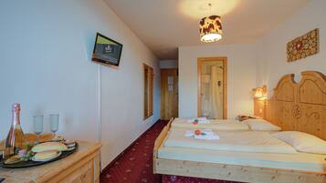 Une chambre d’hôtel avec deux lits, une tête de lit en bois, une armoire en bois, un téléviseur et une moquette rouge.