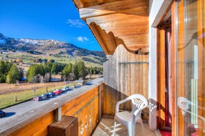 A wooden balcony with a view of a road and mountains. - Hotel Relais Alpin (Ormont-Dessous)