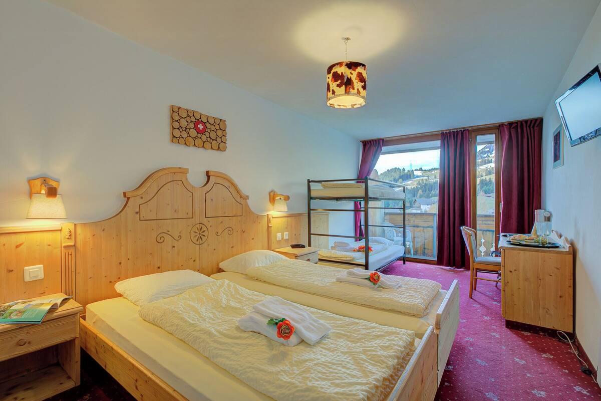 Habitación de hotel con dos camas, un escritorio, una silla, un televisor y vistas a la ciudad.