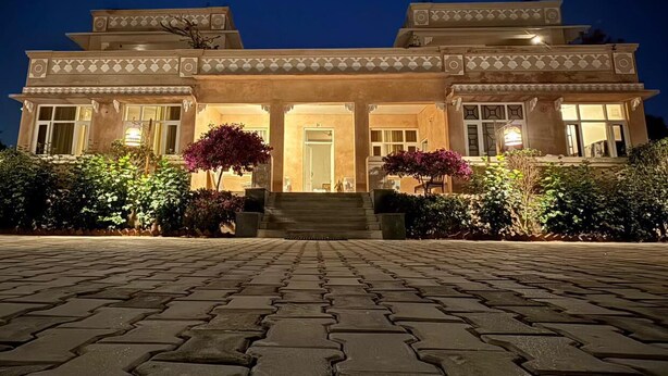 A two-story building with a symmetrical facade, large windows, and a central entrance with steps leading up to it. - The Bagheera Retreat (Pushkar)