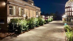 A paved pathway leading to a building with traditional architecture, surrounded by greenery. - The Bagheera Retreat (Pushkar)