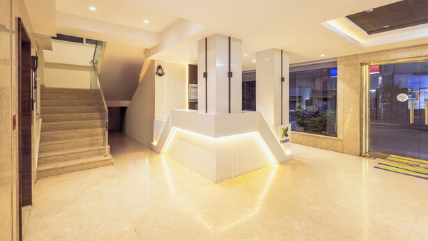 A modern hotel lobby with a marble floor, a reception desk, and a staircase. - Treebo SS Residency Gandhi Nagar (Vijayawada)