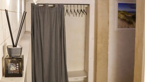 A bathroom with a shower, a towel rack, and a framed picture on the wall.