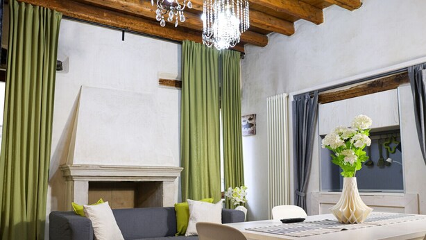 A cozy living room with a fireplace, a dining table, and a chandelier.