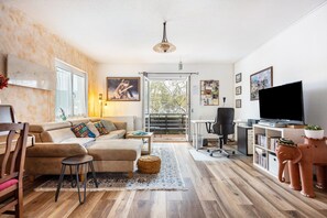 A living room with a sofa, a coffee table, a TV, and a bookshelf. - Charming Boutique Apartment with Balcony and Wi-Fi (Hannover)