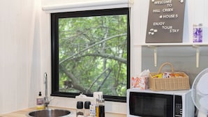 Une cuisine avec une fenêtre, un four à micro-ondes, un évier et un panneau d’accueil.