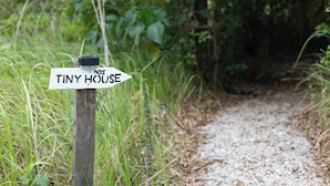 Un panneau indicateur en bois, avec une flèche pointant vers « Tiny House » et portant l’inscription « NOS 5 ».
