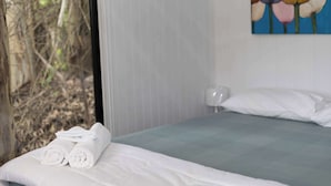 Une chambre d’hôtel avec un lit, une fenêtre donnant sur des arbres et un tableau accroché au mur.