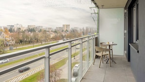 A balcony with a view of a cityscape, a table with chairs, and a glass railing. - Functional Apartment | Large Balcony and Workspace (Warszawa)