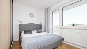 A bedroom with a large bed, a window with a view, and a radiator. - Functional Apartment | Large Balcony and Workspace (Warszawa)