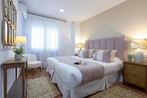 Quarto com uma cama grande, mesas de cabeceira, uma cadeira e um abajur.