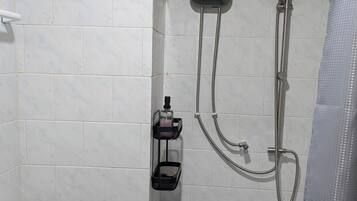Et badeværelse med toilet, bruser med håndbruser og bøjle til håndklæder.