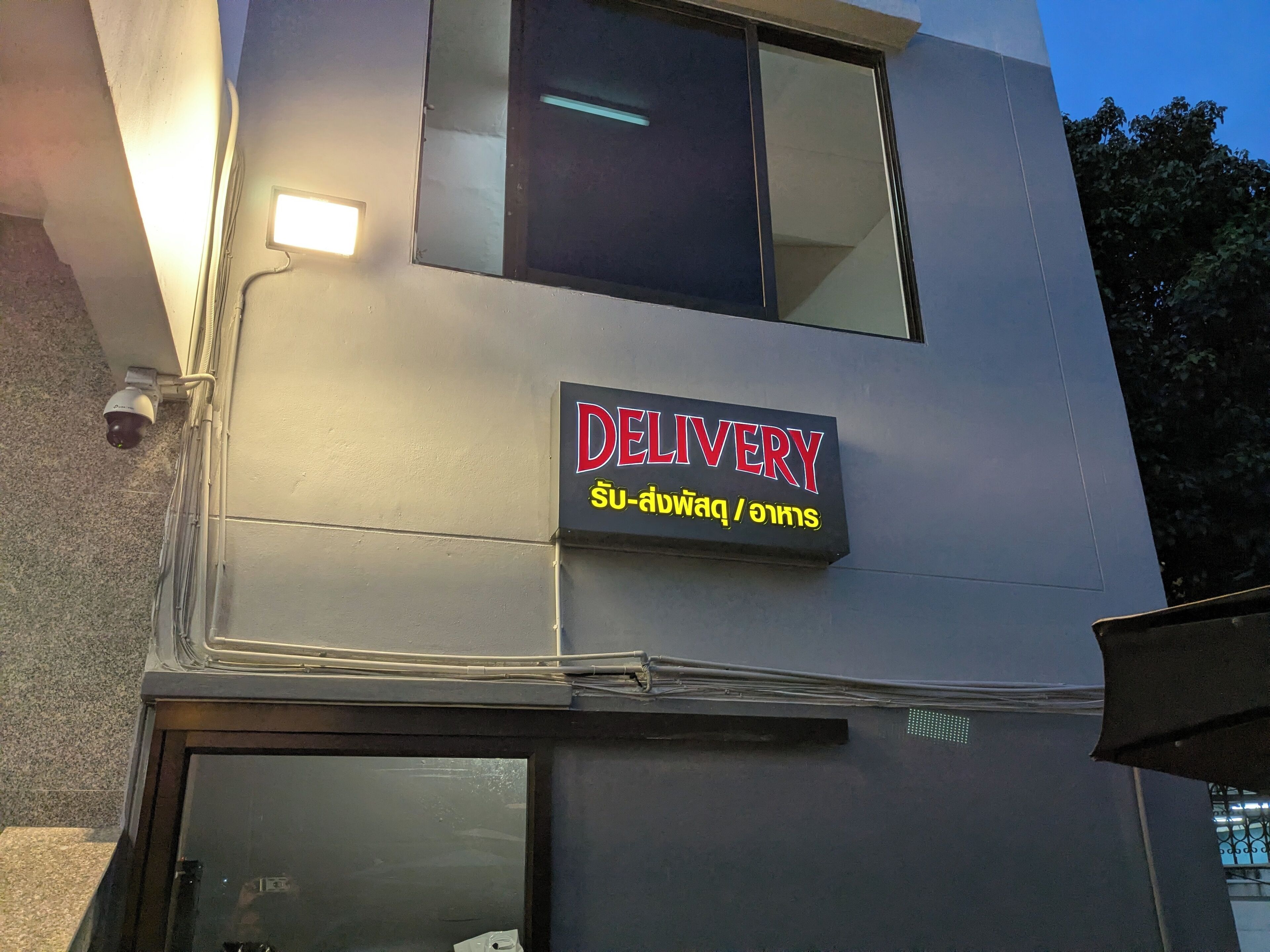 A building with a 'DELIVERY' sign in English and Thai.