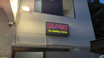 A building with a 'DELIVERY' sign in English and Thai.