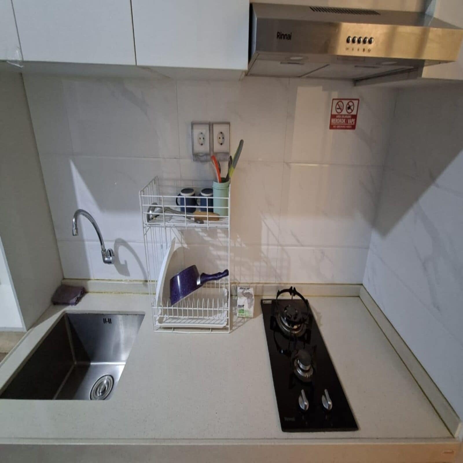 A kitchen with a sink, a stove, and a utensil holder.