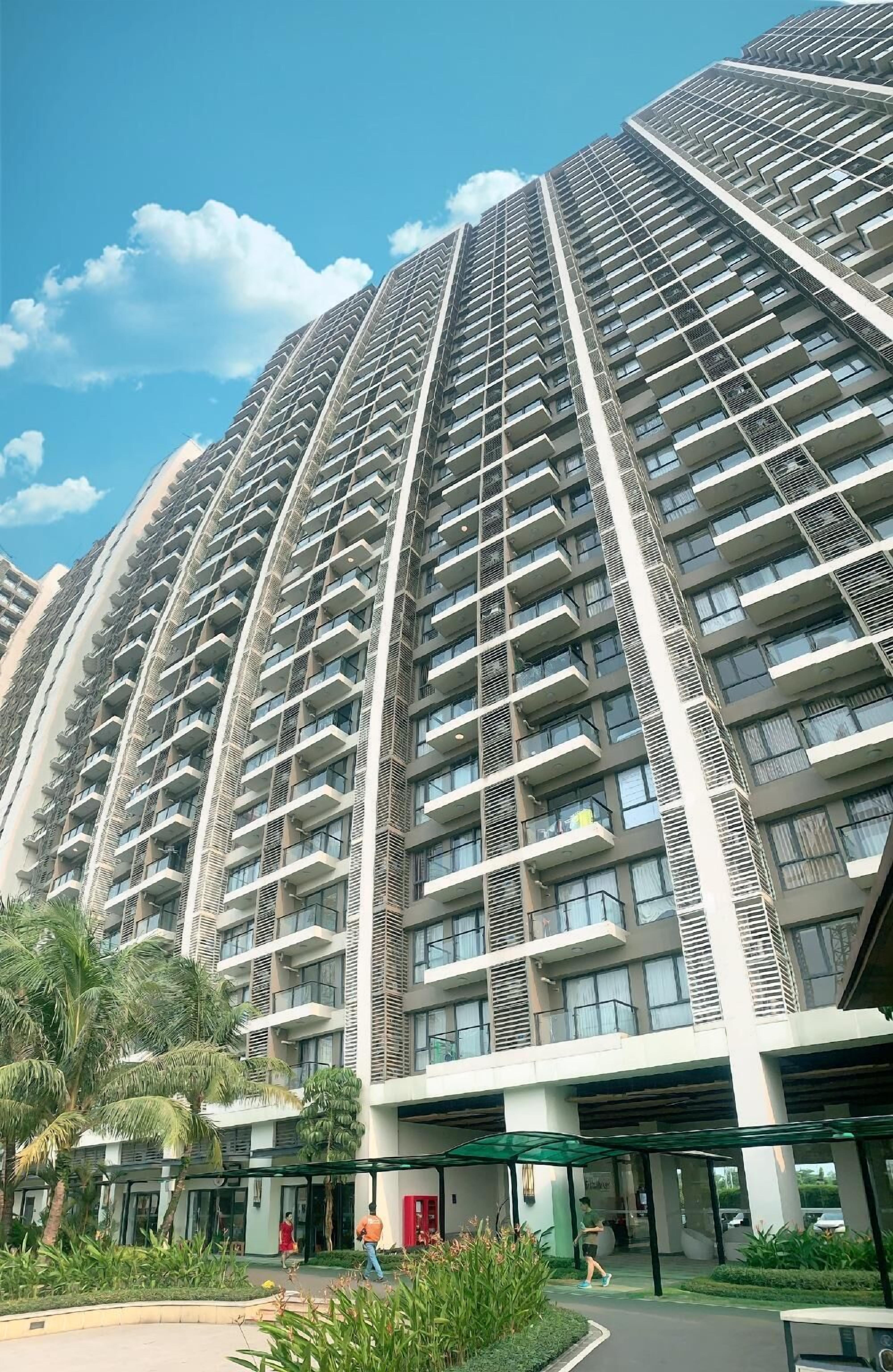 A high-rise residential building with multiple balconies and a covered entrance area.