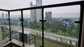 Un edificio alto con balcón de vidrio que da a una autopista y al paisaje urbano.