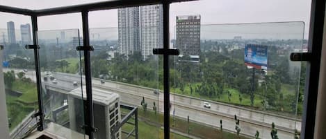 A high-rise building with a glass balcony overlooking a highway and cityscape.